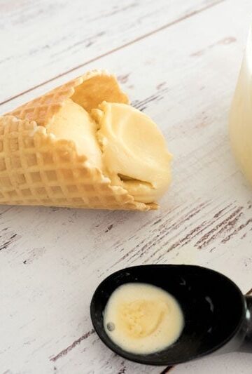 Baileys Ice Cream in a bowl, sugar cones and scoop on light background