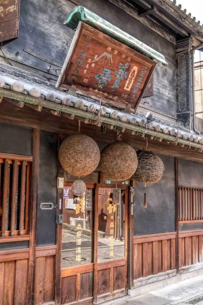 The front of traditional wooden building used by Morita sake brewery in Kurashiki with the 3 cedar balls in the doorway