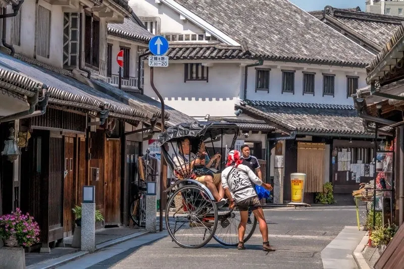 A rickshaw is pulled by hand through the heritage streets of Kurashiki