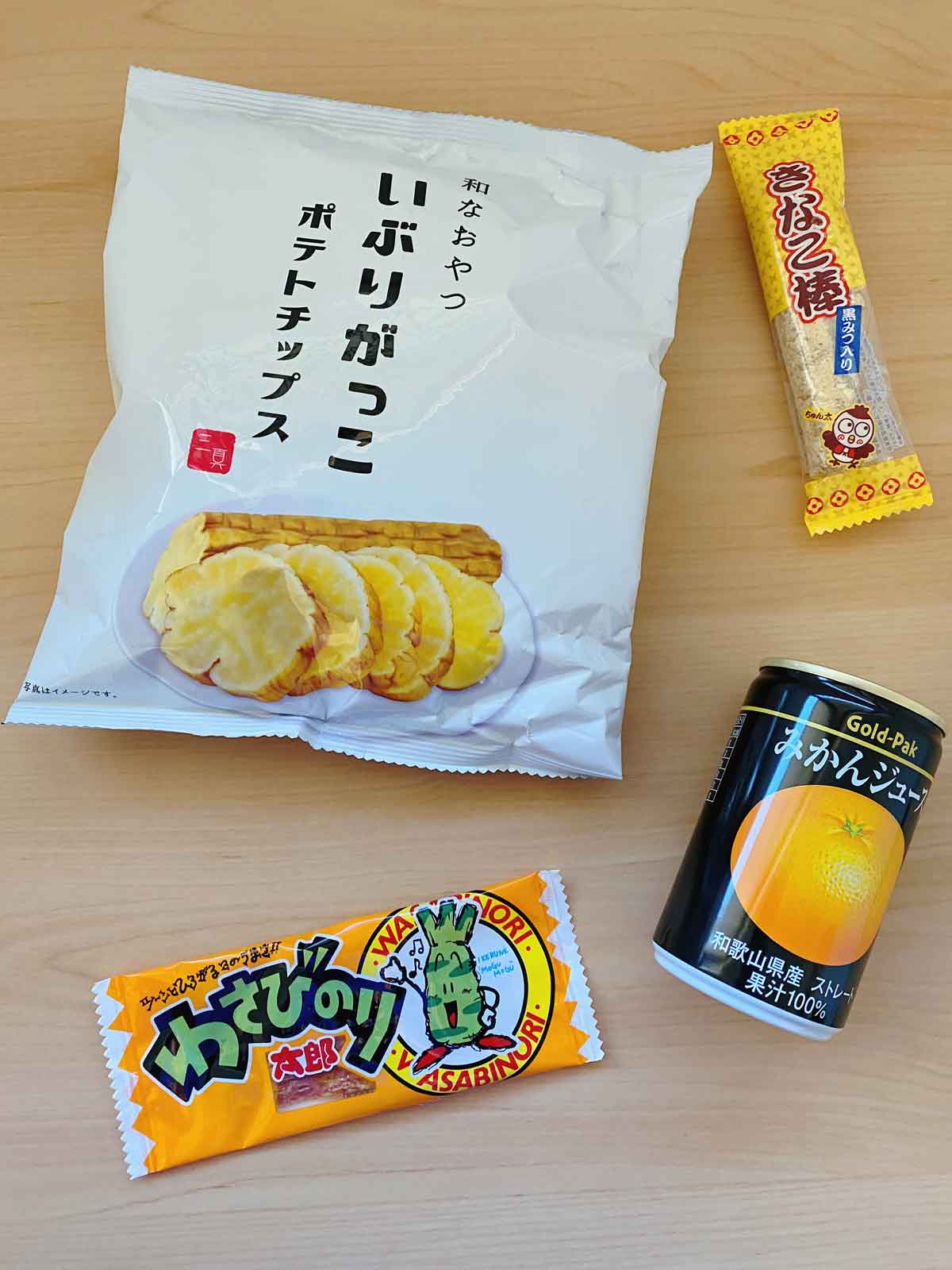 Conteúdo da Tokyo Treat Box - chips de Daikon em conserva, açúcar mascavo e palito Kinako Mochi, carne seca de peixe Wasabi e suco de Mikan