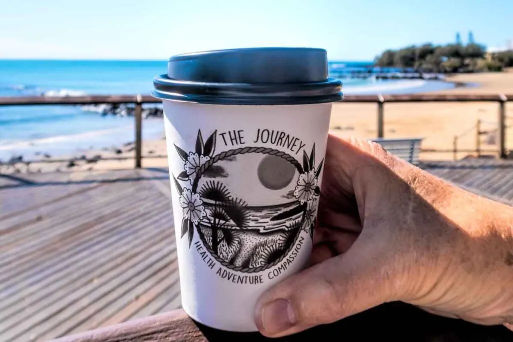 Takeaway coffee cup with Bargara beach behind